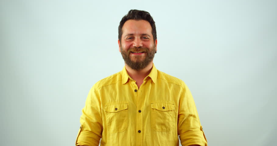 A middle-aged blonde man looks at the camera and smiles in slow motion