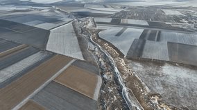 Bird eye 4k video in winter. Drone flying above the agriculture field covered with snow
