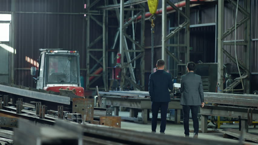 Two Caucasian men investor and engineer walking through the manufacturing factory and discussing about the work concept of team work | Shutterstock HD Video #1111355309