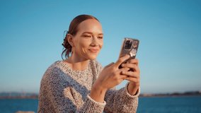 Seaside woman looking smartphone in sunset sunlight closeup. Happy travel girl resting summer evening messaging scrolling mobile phone online. Joyful beautiful model enjoying lake weekend outdoors - Powered by Shutterstock - Get 15% off with code: PIKWIZARD15