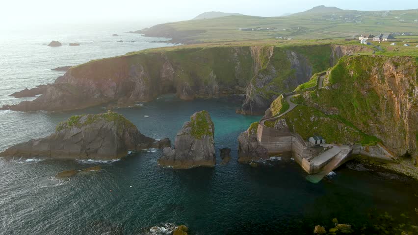 Dunquin or Dun Chaoin pier, Ireland's Sheep Highway. Aerial view of narrow pathway winding down to the pier, ocean coastline, cliffs. Popular iconic location on Slea Head Drive and Wild Atlantic Way.
