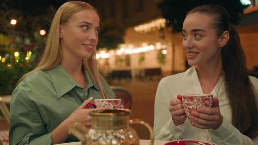 Two Caucasian European happy women drinking tea cafe city street outdoors evening friends talking chatting smiling laughing discuss restaurant relaxation meeting enjoying together urban summer weekend Royalty-Free Stock Footage #1111358155
