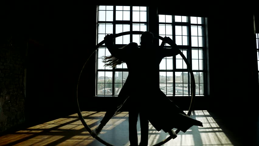 Silhouette of man and woman spinning on hoop in room, mysterious dance performance | Shutterstock HD Video #1111365451