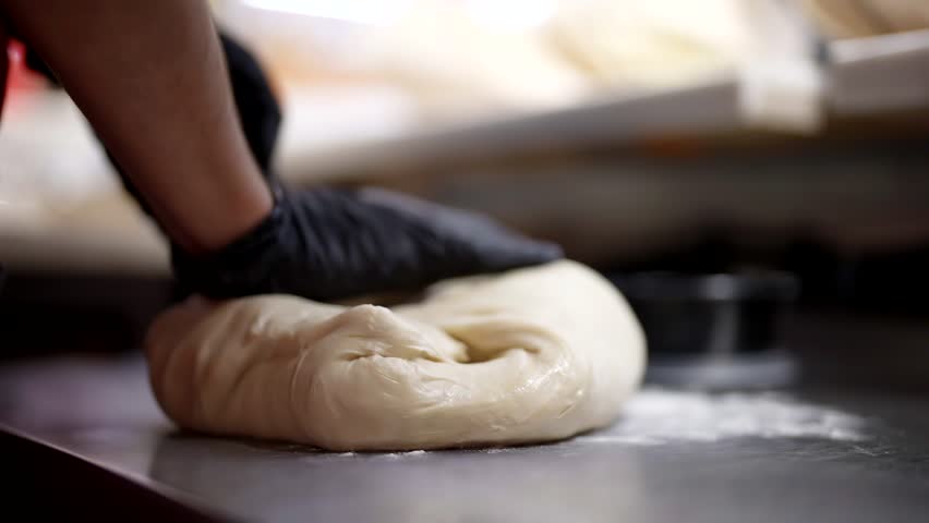 Cook kneading dough for pizza in Italian restaurant, closeup view of hands in gloves in kitchen | Shutterstock HD Video #1111365499