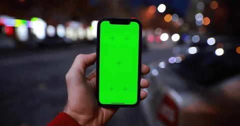 POV male hand holding smartphone with green screen chroma key near night road Video de stock