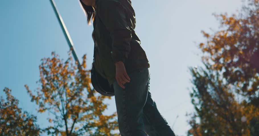 low angle shot of a beautiful Ukrainian girl raises her head and looks at the Ukrainian flag, which flutters in the wind on a high flagpole against the background of the blue sky on a sunny autumn day Royalty-Free Stock Footage #1111369687