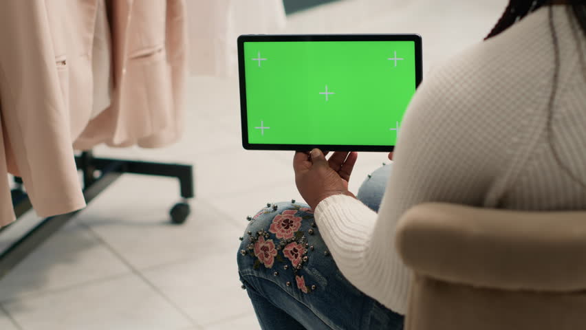 African american woman holding green screen tablet in luxury clothing shop with elegant formalwear women clothes. BIPOC buyer with chroma key digital device in fashion boutique
