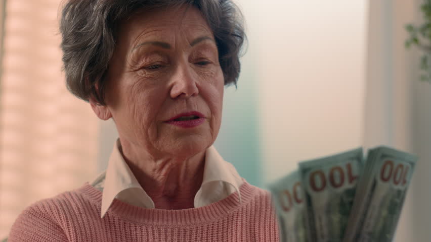 Happy smiling rich Caucasian old woman count money at home bills winning bonus grandmother counting dollars senior granny holding cash old female elderly retired lady with banknotes financial savings Royalty-Free Stock Footage #1111375843