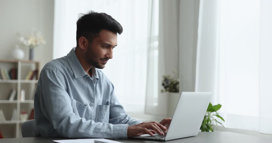 Serious young Indian freelance professional man typing on laptop at home workplace table, keeping focus on work tasks, chatting, using Internet technology for job communication Royalty-Free Stock Footage #1111376707