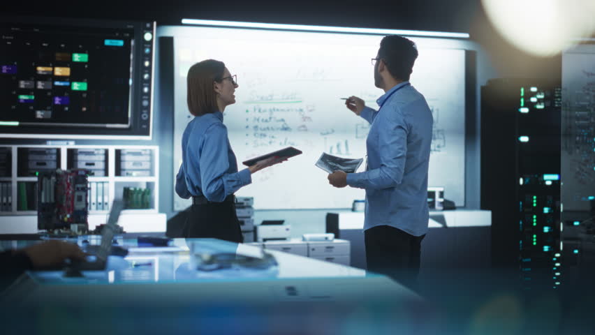 In Technological Research Facility: Portrait of a Team of Two Professional Engineers Using Digital Tablet and White Board to Discuss the Manufacturing Plan for Product Development