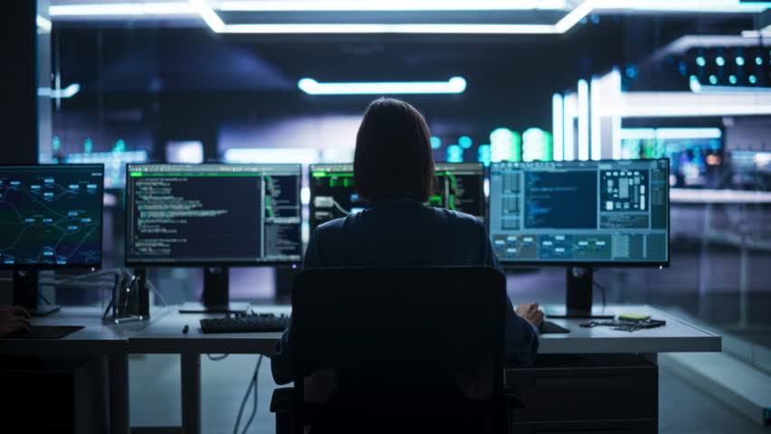 Back View of Female Telecommunications Manager Working in Research and Development Facility on a Desktop Computer in Modern Office. Focused Software Engineer Updating Server System Database. Zoom Out - Powered by Shutterstock - Get 15% off with code: PIKWIZARD15