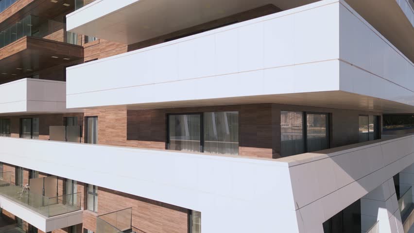 A drone flies along the facade of a modern hotel. Windows and balconies are visible Royalty-Free Stock Footage #1111382819