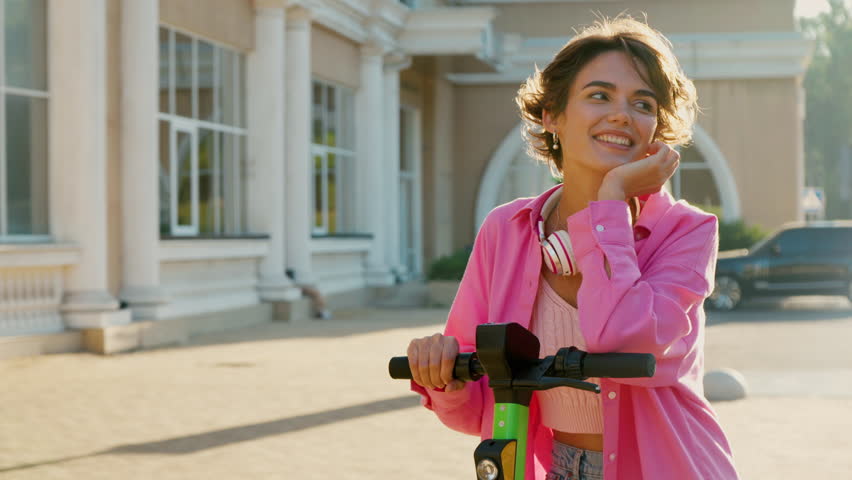 Portrait of beautiful caucasian woman with shared electric push scooter in the city. Rental electric transportation.