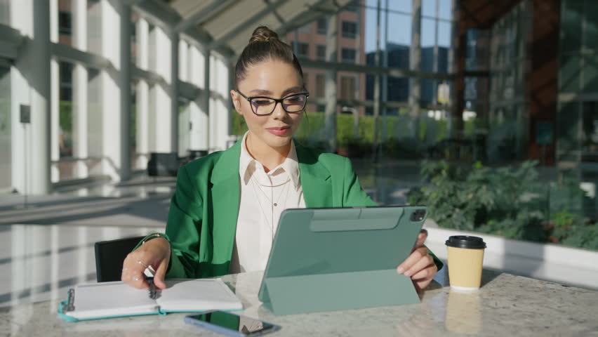 Stylish young focused female executive manager sitting at desk working in contemporary corporation office. Fashionable businesswoman thinking about project while using business technologies concept Royalty-Free Stock Footage #1111401899