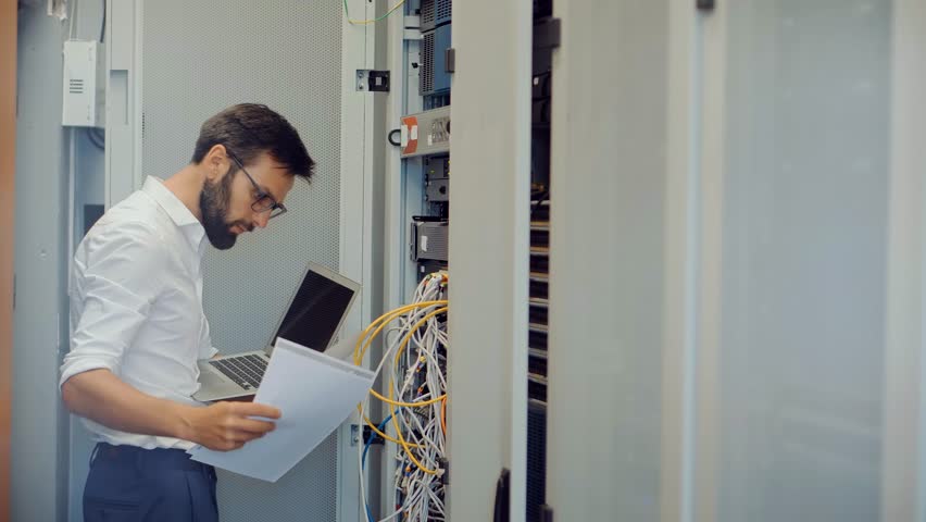 System Engineer Control Room IT Administrator. Server Engineer Work On Laptop in Data Center. Male Server IT Engineer Work Data Center. Man Work In Server Room. Male Typing On Laptop In Server Room Royalty-Free Stock Footage #1111412621