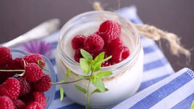 Sweet cooked homemade yogurt with fresh raspberries in a glass jar.
