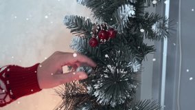 Christmas holiday background with garland of fir branches with berries and pine cones close up, straightened by female hands in red, festival invitation to Christmas party with effect of falling snow. - Powered by Shutterstock - Get 15% off with code: PIKWIZARD15