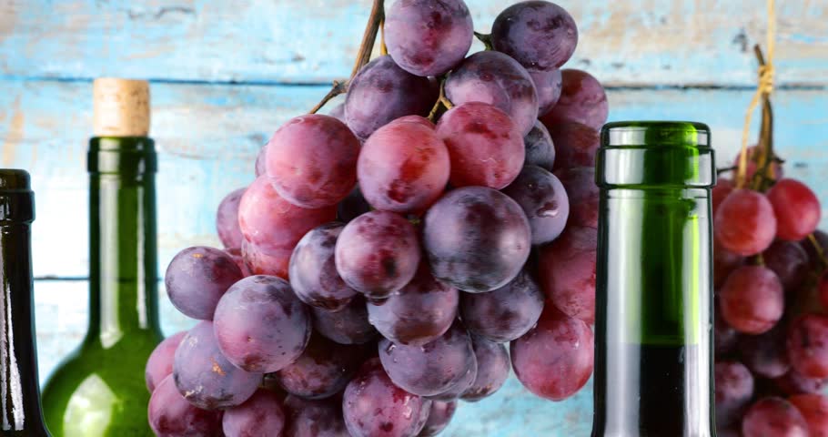 Pink grapes and wine bottles on a blue vintage wooden background.	