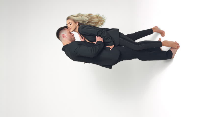 Caucasian young couple wearing black suits stand in studio. Couple stroking each other. White backdrop. Vertical screen. Royalty-Free Stock Footage #1111419427