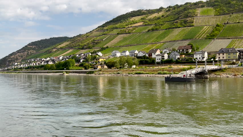 Traveling along the Rhine River with scenic views of the quaint town of Lorch, Germany. Views of European architecture, churches, castles and agricultural fields on the sloping land.