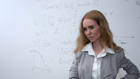 Caucasian female teacher stands at a white board with written formulas.  - Powered by Shutterstock - Get 15% off with code: PIKWIZARD15