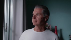 Contemplative middle-aged man standing by window gazing out with pensive thoughtful expression. Gray hair male person thinking about life - Powered by Shutterstock - Get 15% off with code: PIKWIZARD15
