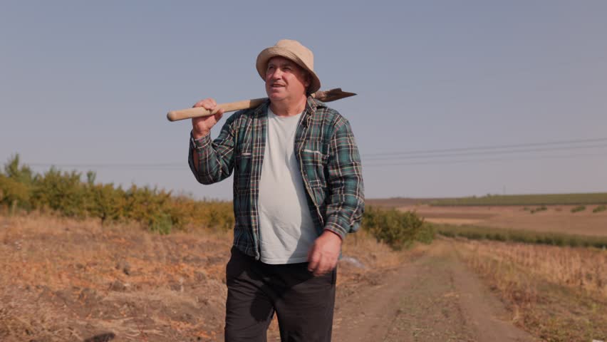 Agricultural Expertise An Elderly Farmer Walks the Fields, Shovel Ready for Tilling the Rich Farmland. Captured in 4K Elderly Worker with Shovel in Countryside
