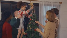 Multi-ethnic family and young daughter decorate Christmas tree in house. Young little daughter feeling happy and excited to celebrate holiday Christmas Thanksgiving party with parents together at home - Powered by Shutterstock - Get 15% off with code: PIKWIZARD15