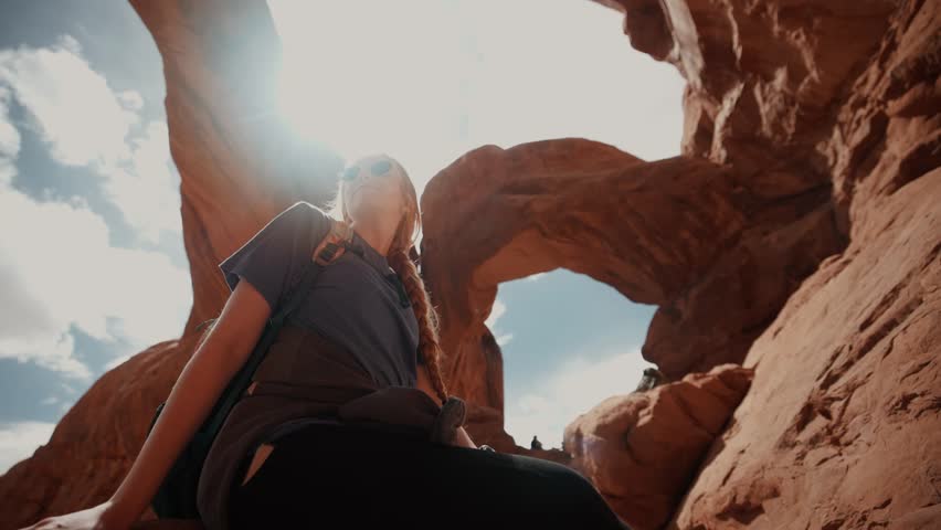 Female hiker looking around underneath beautiful natural canyon arches