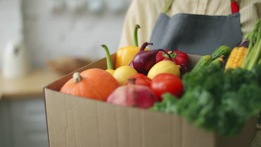 organic fresh food. a cardboard box with groceries close up. online food delivery. fresh vegetables and fruits. local farmers market. fresh produce, tomatoes, corn, asparagus, lemons, peppers 