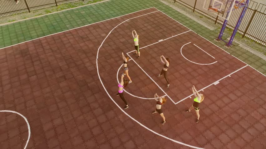 Sportive and smile. Group of athletic young women in sportswear doing physical exercises with coach in green summer park of the university. Team of Girls doing sport and physical exercises outdoor | Shutterstock HD Video #1111438973