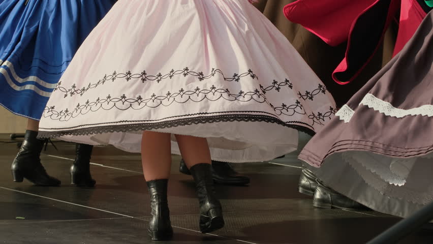 People in national Polish costumes perform traditional dances in slow motion. A close-up shot of the folk dance performed by the ensemble in traditional folklore costumes. Cultural heritage concept