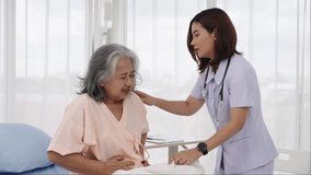 Handheld shot, Asian elderly patient with stomachache. A nurse or caregiver for an elderly patient is helping a patient with severe stomach problems. Nurses care for patients in hospitals or clinics.