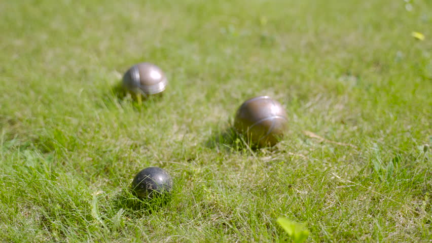 Close-up view of three metal petanque balls on the grass, then the player throw another ball nearby | Shutterstock HD Video #1111448087
