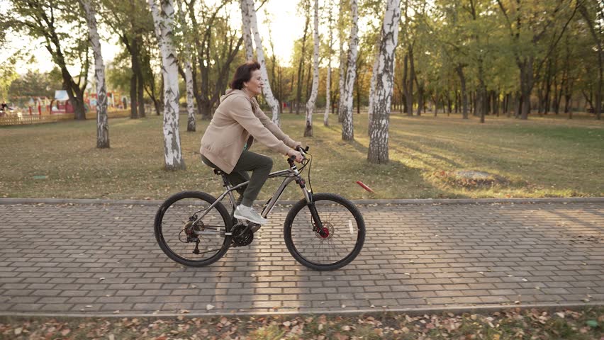 Mature woman riding bicycle at the sunset | Shutterstock HD Video #1111452887