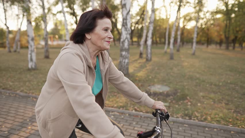 Elderly woman riding bicycle at park | Shutterstock HD Video #1111452889
