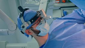 Bearded male surgeon wearing eyeglasses and device glasses at neurosurgery. Close portrait of a doctor assisting at operation. Vertical video.