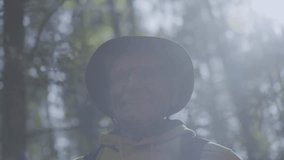 Senior man wearing hat stands in natural forest illuminated by bright sun. Sunlight breaks through tall tree branches in spring forest - Powered by Shutterstock - Get 15% off with code: PIKWIZARD15