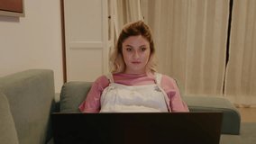 Portrait of pregnant woman interested in watching laptop smiles when the baby kicks. Pregnant woman using laptop at home. Pregnancy concept. - Powered by Shutterstock - Get 15% off with code: PIKWIZARD15