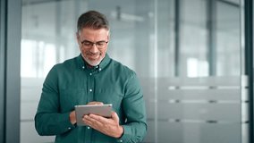 Smiling busy middle aged business man investor using tablet computer, mature older businessman executive manager looking at tab satisfied with finance trading market standing in office. - Powered by Shutterstock - Get 15% off with code: PIKWIZARD15