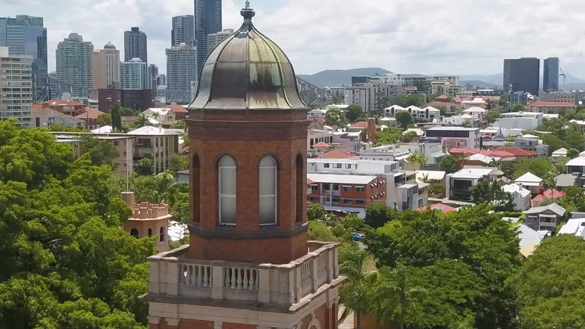 Orbit around church tower with Brisbane city skyline behind, aerial