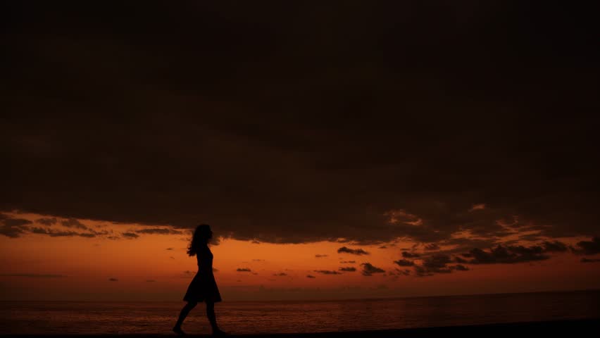The silhouette of a lonely woman walking at sunset along the seashore. Retreat. Privacy with nature | Shutterstock HD Video #1111457587