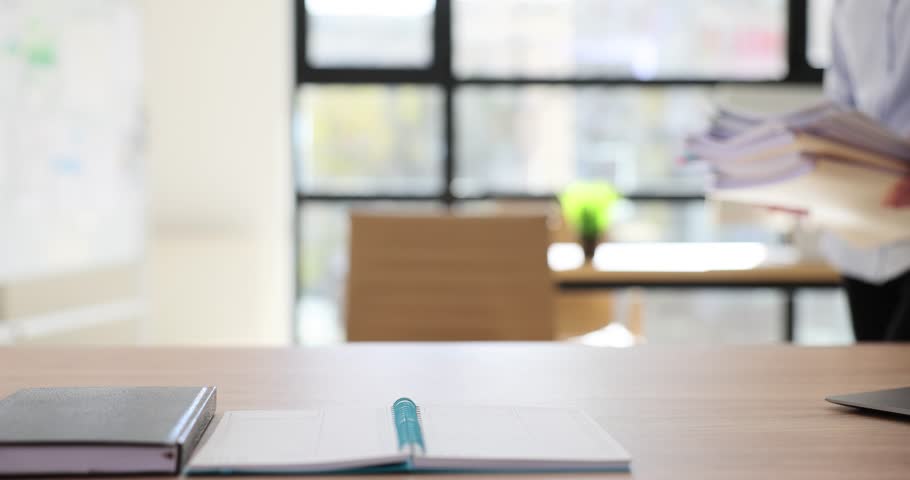 Female manager puts stack of office documents on table. Workplace with office papers and secretary