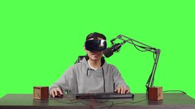 Streamer broadcasting live online games from his desktop while participating online using virtual reality equipment. Asian person streaming videogames, content creator on greenscreen.