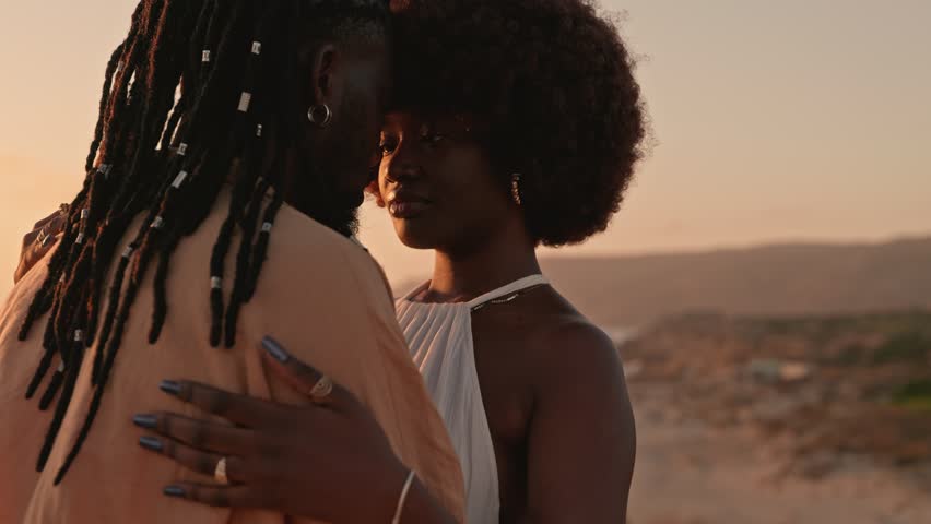 A closeup shot capturing the intimate moment of a stylish African black couple embracing and gazing into each other's eyes against a beautiful sunset backdrop Royalty-Free Stock Footage #1111479151
