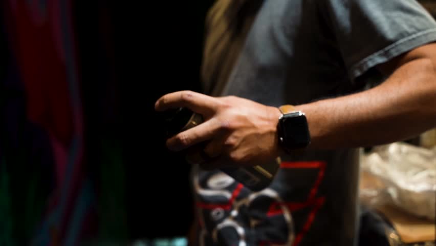 Graffiti Artist Shaking a Spray Can Preparing to Paint Street Art on a Mural