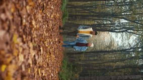 Vertical video of couple spending time together walking in forest at morning.