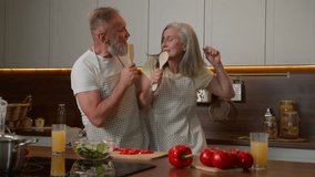 Middle-aged retired couple Caucasian happy family older husband wife singing song having fun at kitchen together funny cooking fresh healthy vegetables mature woman and man sing at kitchenware spoons - Powered by Shutterstock - Get 15% off with code: PIKWIZARD15