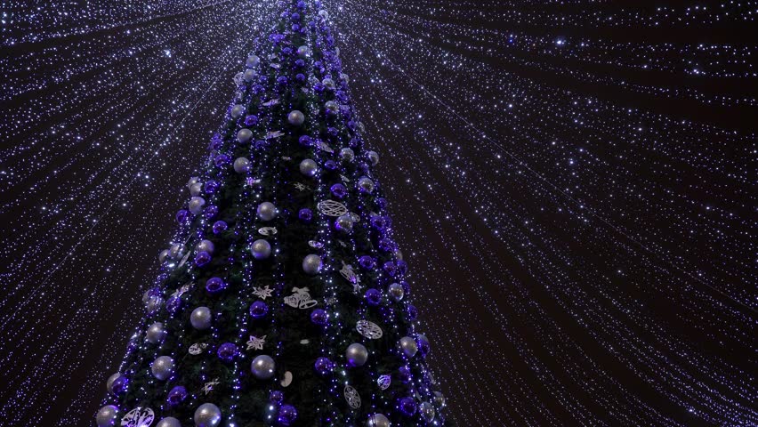 Decorated Christmas tree is decorated with backlit sparkles for a Christmas party in the city center. Tall christmas tree decorated and illuminated outdoors. 4k footage | Shutterstock HD Video #1111500759