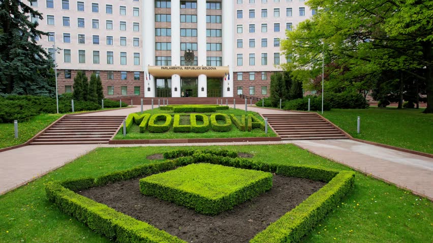Panoramic aerial drone view of front of Parliament Building of Moldova in Chisinau, spring time. Main inscription at entrance to building of Parliament of Moldova - Parlamentul Republicii Moldova. 4K.